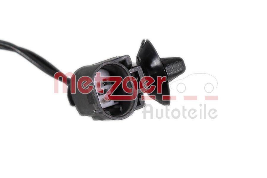 Ein schwarzer Autosensor mit einem Steckverbinder ist zu sehen. Im Hintergrund ist teilweise das Logo von 'Metzger Autoteile' erkennbar.