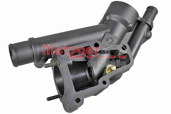 Ein schwarzes Metallautoteil mit der Beschriftung 'Metzger Autoteile', das mehrere Befestigungslöcher und ein Ventil aufweist und typischerweise in Automotive-Systemen verwendet wird.