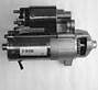 Eine mechanische Vorrichtung, möglicherweise ein Anlassermotor, in einem Graustufenbild, die einen zylindrischen Metallkörper mit Zahnrädern und elektrischen Komponenten zeigt.