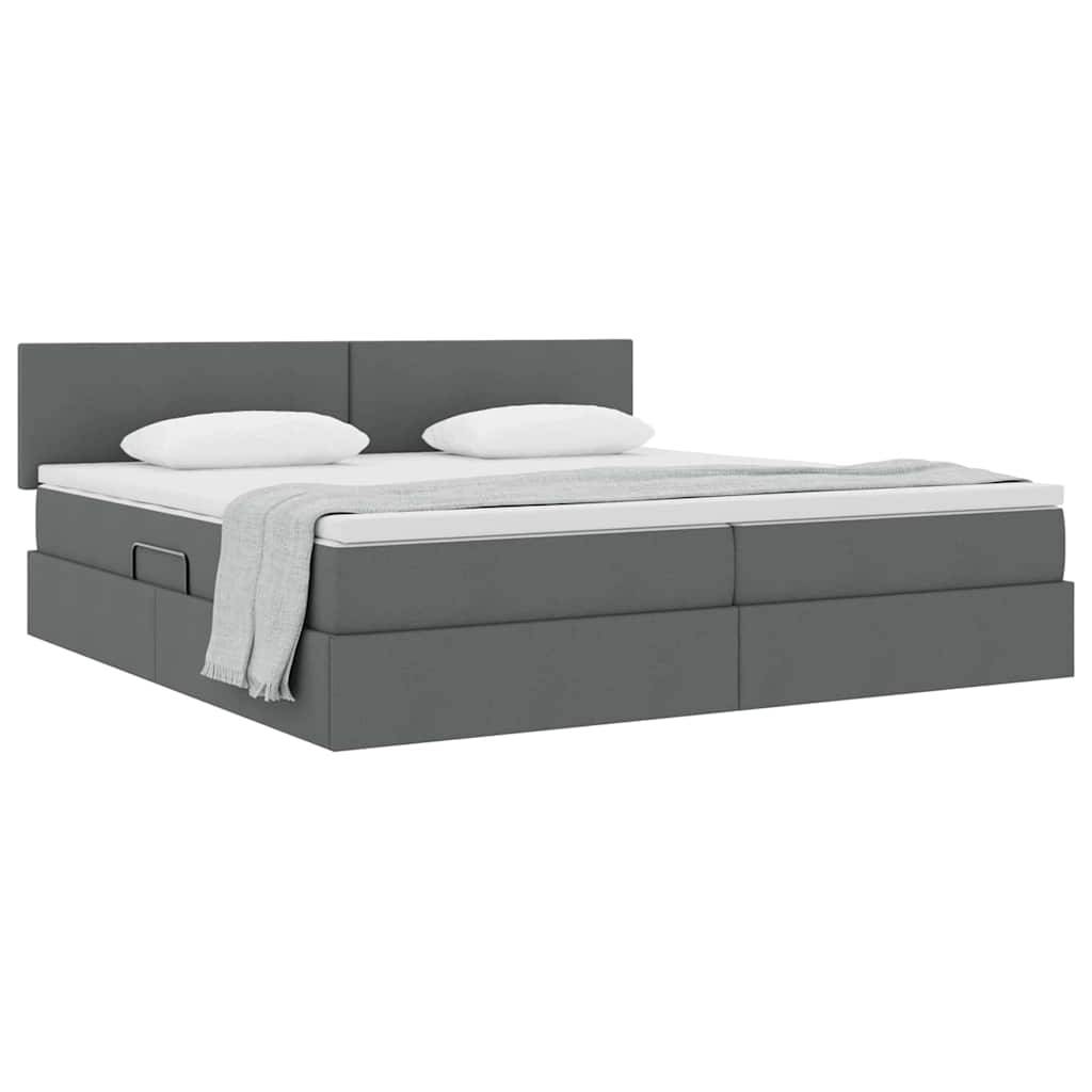 Ein modernes graues Bett mit hohem Kopfteil, auf dem eine ordentlich gefaltete beige Decke und zwei weiße Kissen oben liegen.