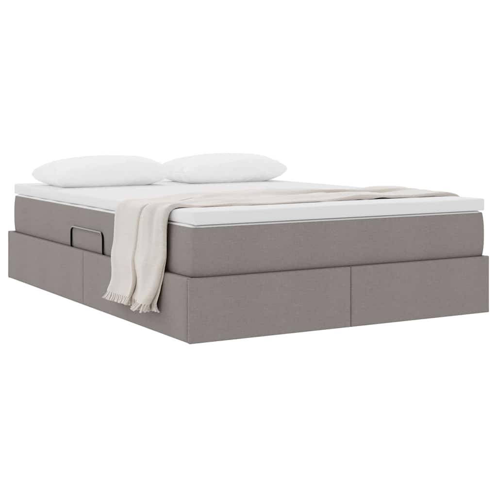 Ein Bett mit Stauraum, dessen Rahmen mit grauem Polsterstoff bezogen ist, zwei weiße Kissen und eine beige Decke, die über eine Seite gehängt ist.
