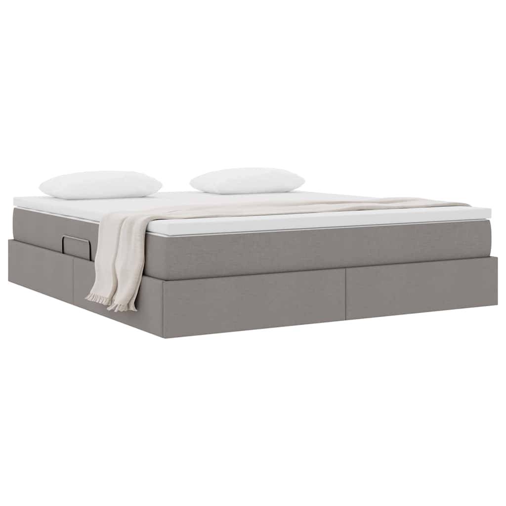Ein modernes graues Plattformbett mit einer weißen Matratze, zwei weißen Kissen und einer beigen Decke, die ordentlich über eine Ecke drapiert ist.