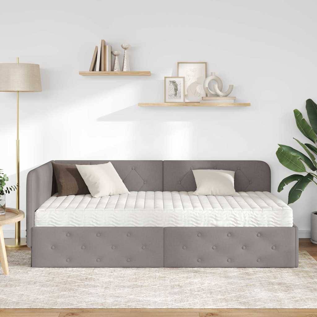 Ein modernes Schlafzimmer zeigt ein grau gepolstertes Tagesbett mit weißer Bettwäsche, flankiert von einer Stehlampe. Regale mit Dekorationselementen sind an der Wand darüber angebracht.