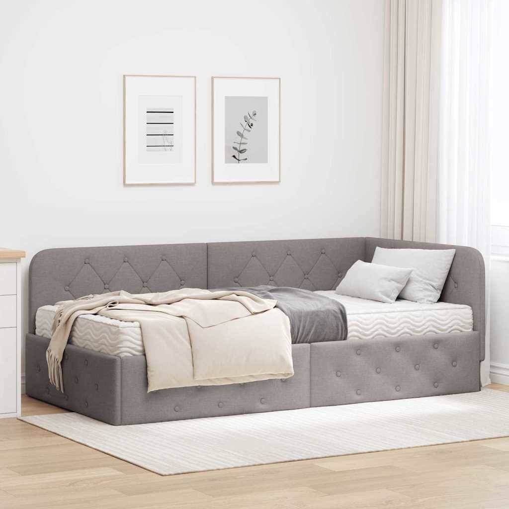 Ein modernes graues Tagesbett mit gesteppter Polsterung, gestylt mit beiger und grauer Bettwäsche, positioniert in einem hellen Raum mit gerahmten Wandkunstwerken.