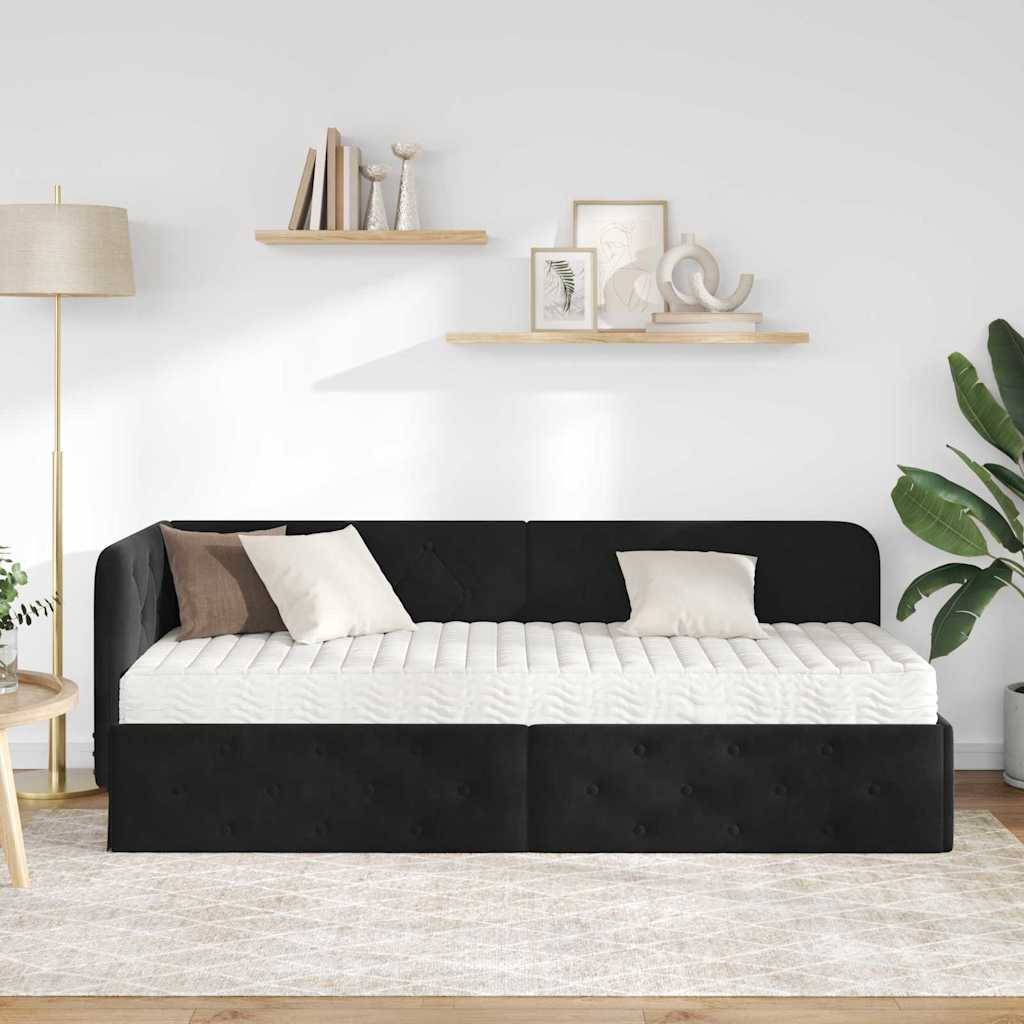 Schwarzes gepolstertes Tagesbett mit weißer Matratze, Kissen, Stehleuchte, Wandregalen und Pflanzen in einem hellen minimalistische Raum.