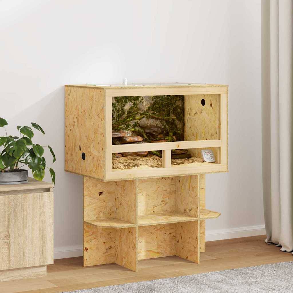 Ein Terrariumständer aus Holz mit einer Glaseinheit oben drauf, in der ein kleiner Echse sitzt, neben einer Topfpflanze in einem Raum.