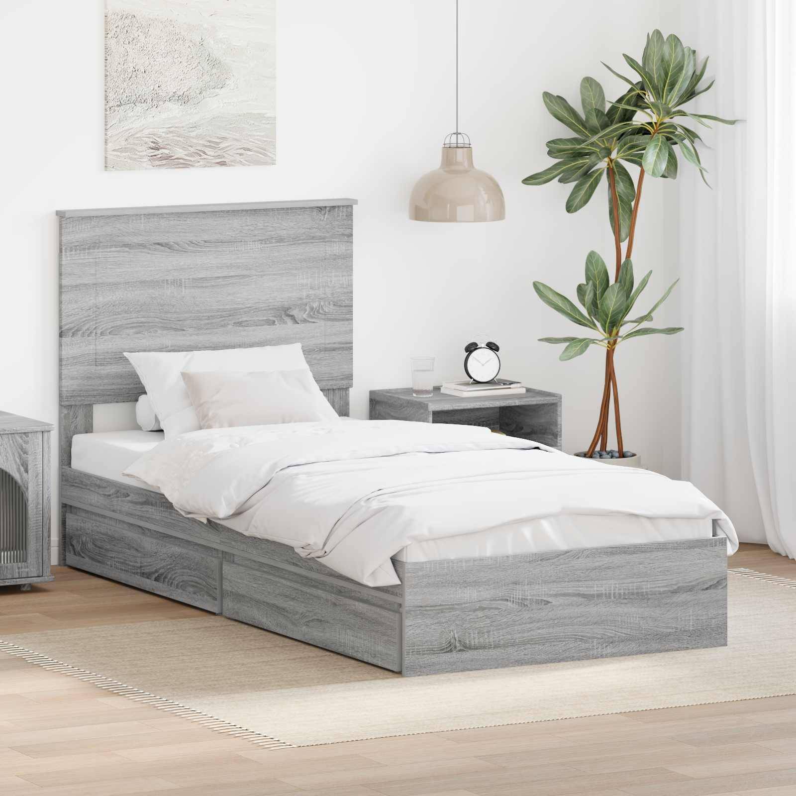 Ein modernes Schlafzimmer mit grauem Holzbett, weißer Bettwäsche, passendem Nachttisch, Topfpflanze, Wandkunst und Pendelleuchte.