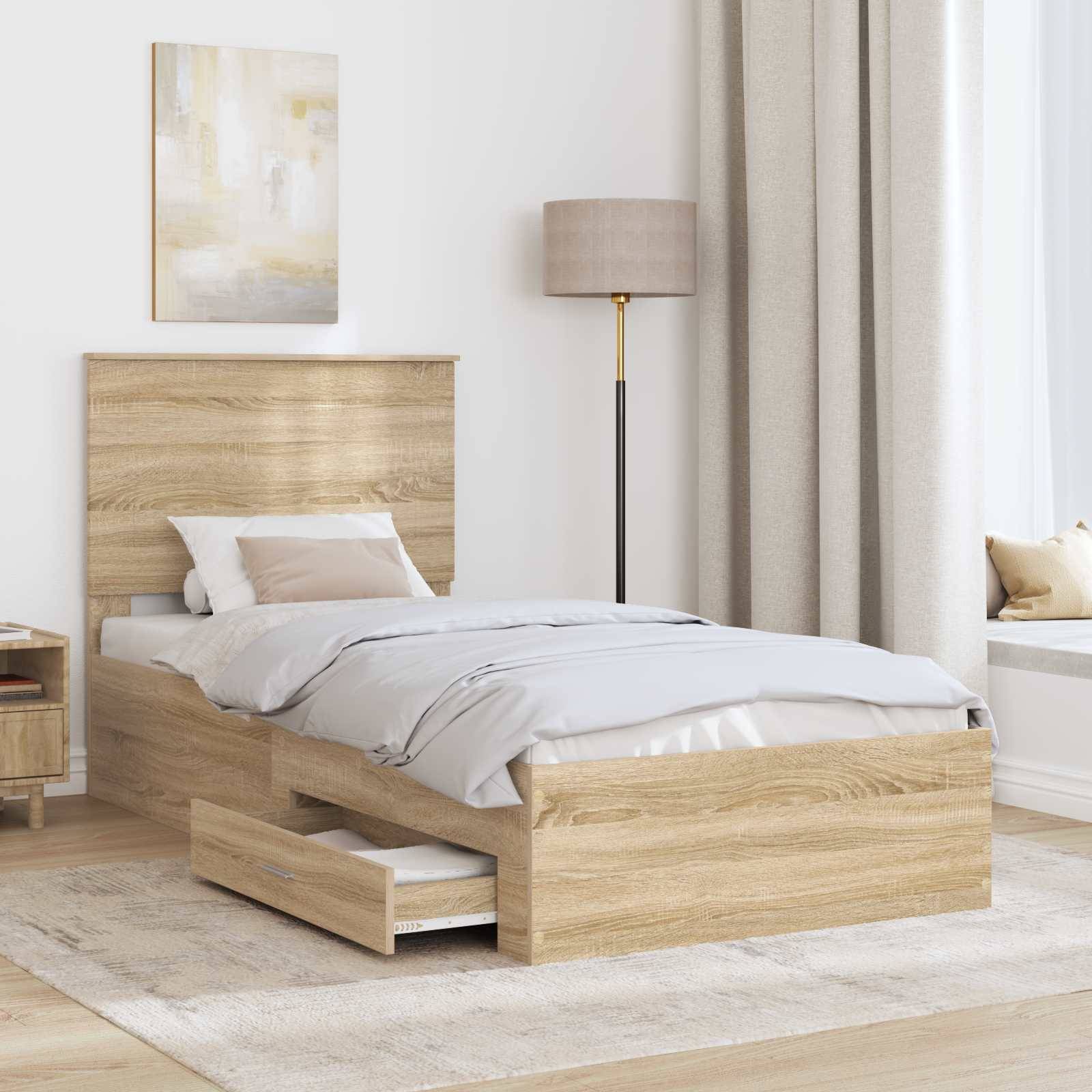 Ein minimalistisches Schlafzimmer mit einem Holzbett, beiger Bettwäsche und einer Stehlampe. Eine Schublade unter dem Bett ist teilweise geöffnet und gibt Einblicke in den Stauraum.