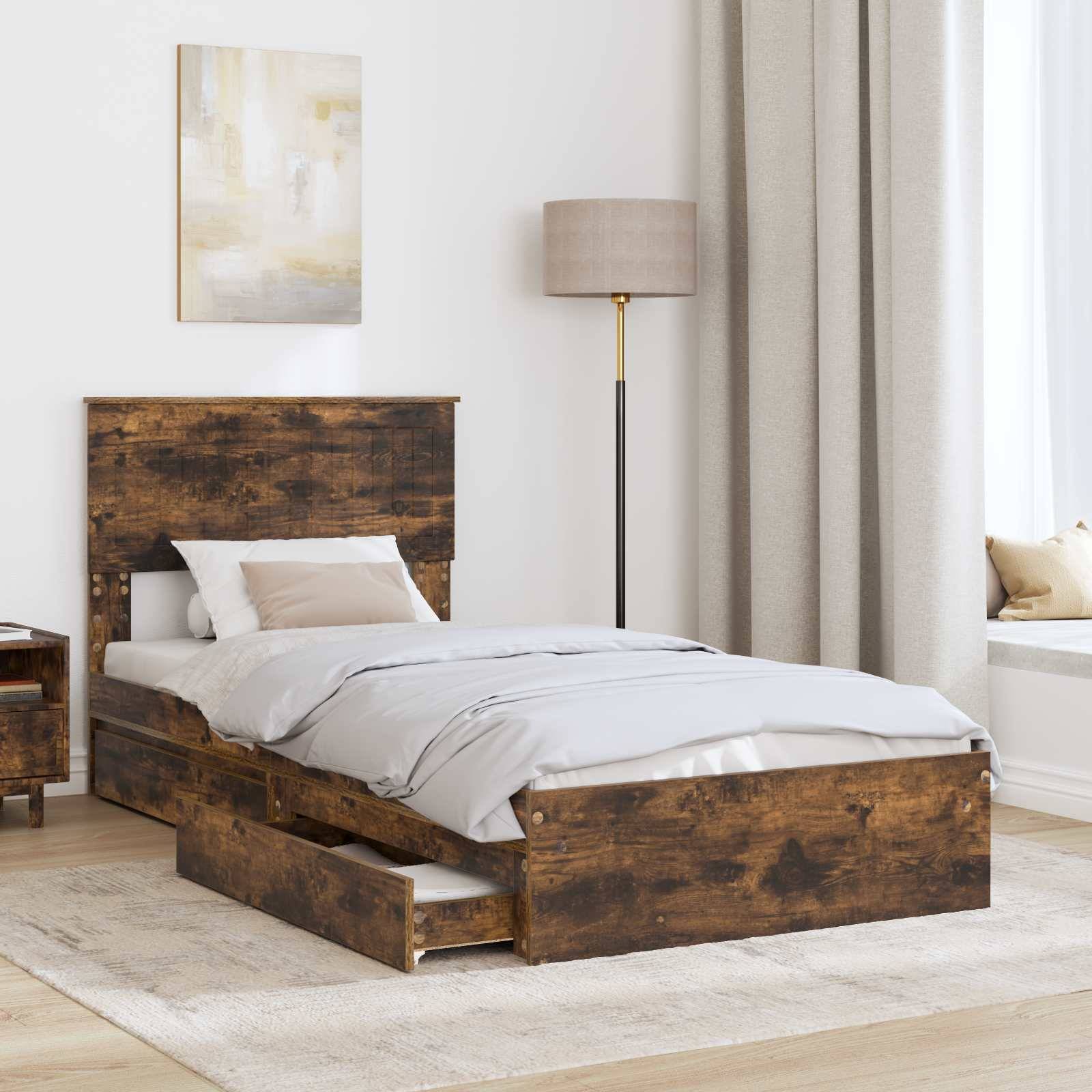 Ein rustikales Holzbett mit einer grauen Daunendecke und weißen Kissen verfügt über eine Schublade darunter, die sich verschieben lässt. Daneben gibt es ein passendes Nachttischchen, eine Lampe und ein Gemälde an der Wand.