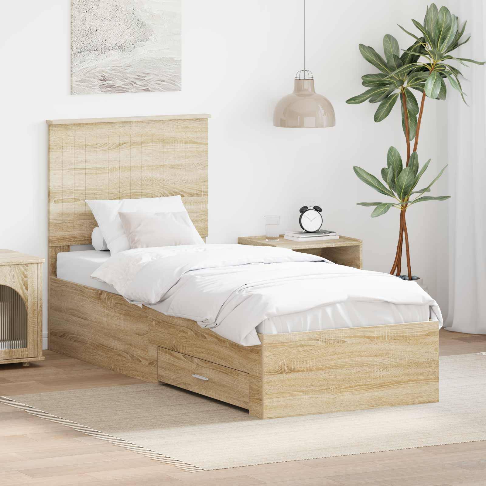 Ein aufgeräumtes Schlafzimmer hat ein Holz-Einzelbett mit weißer Bettwäsche, einen Nachttisch mit einer Uhr, einen Rattanschrank, eine Zimmerpflanze und eine Pendelleuchte.
