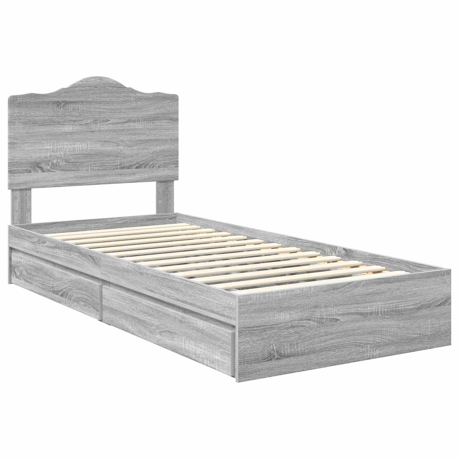 Ein grauer Holzbettrahmen mit hohem Kopfteil, Lattenrost und zwei Bettkasten-Schubladen, von der Seite aufgenommen.