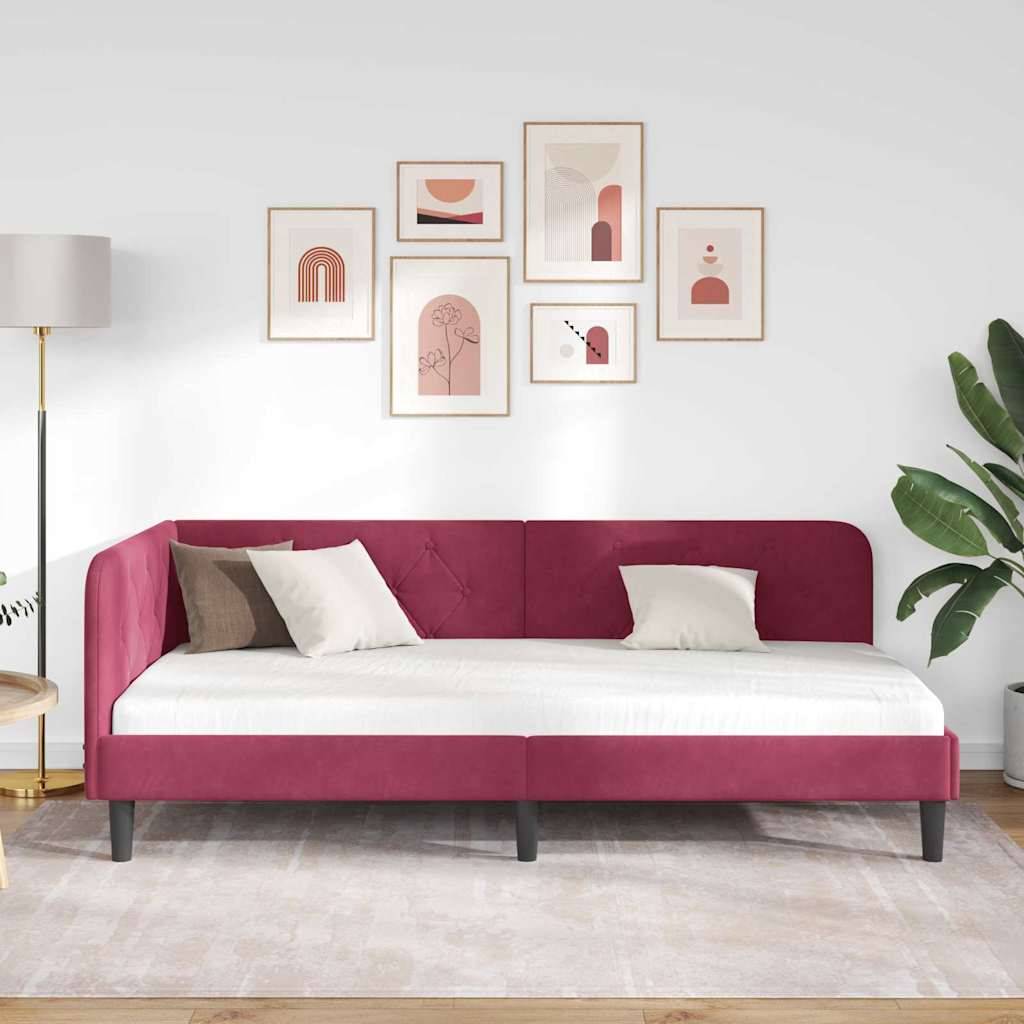 Ein modernes Wohnzimmer verfügt über ein rotes Schlafsofa mit weißen Kissen, eine Galeriewand mit abstrakter Kunst, eine Stehlampe und eine große Pflanze.