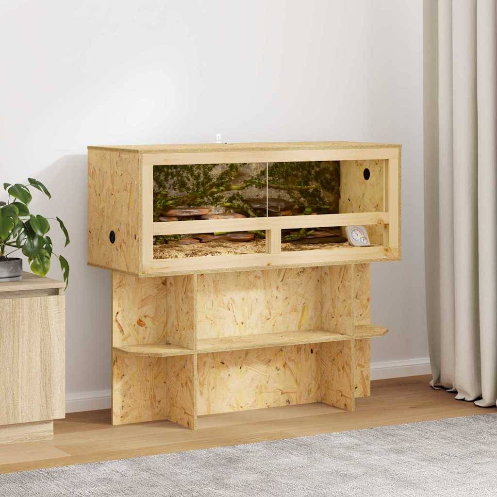 Ein Terrarium aus Holz für Reptilien mit Glastüren steht im Wohnzimmer. Es verfügt über zwei Abteile und befindet sich neben einem Schrank und einer Pflanze.