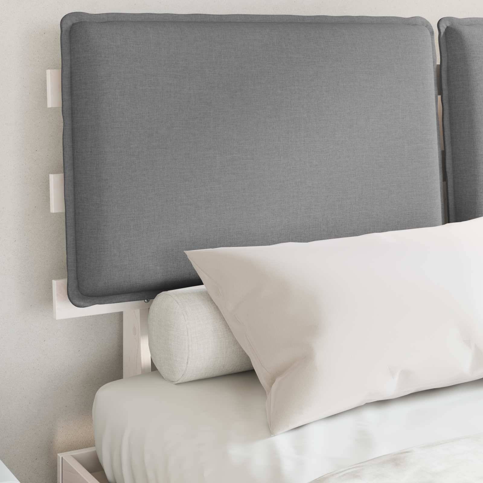Ein ordentlich gemachtes Bett mit einem gepolsterten Kopfteil an einer weißen Wand, ausgestattet mit zwei weißen Kissen und einer hellgrauen Bettdecke.