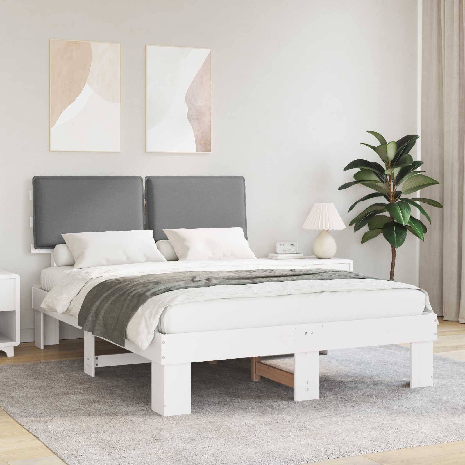Ein modernes Schlafzimmer mit einem weißen Bett, grauem Kopfteil und weißer Bettwäsche. Zwei abstrakte Gemälde hängen über dem Bett. Eine Pflanze und eine Lampe stehen auf einem Beistelltisch.