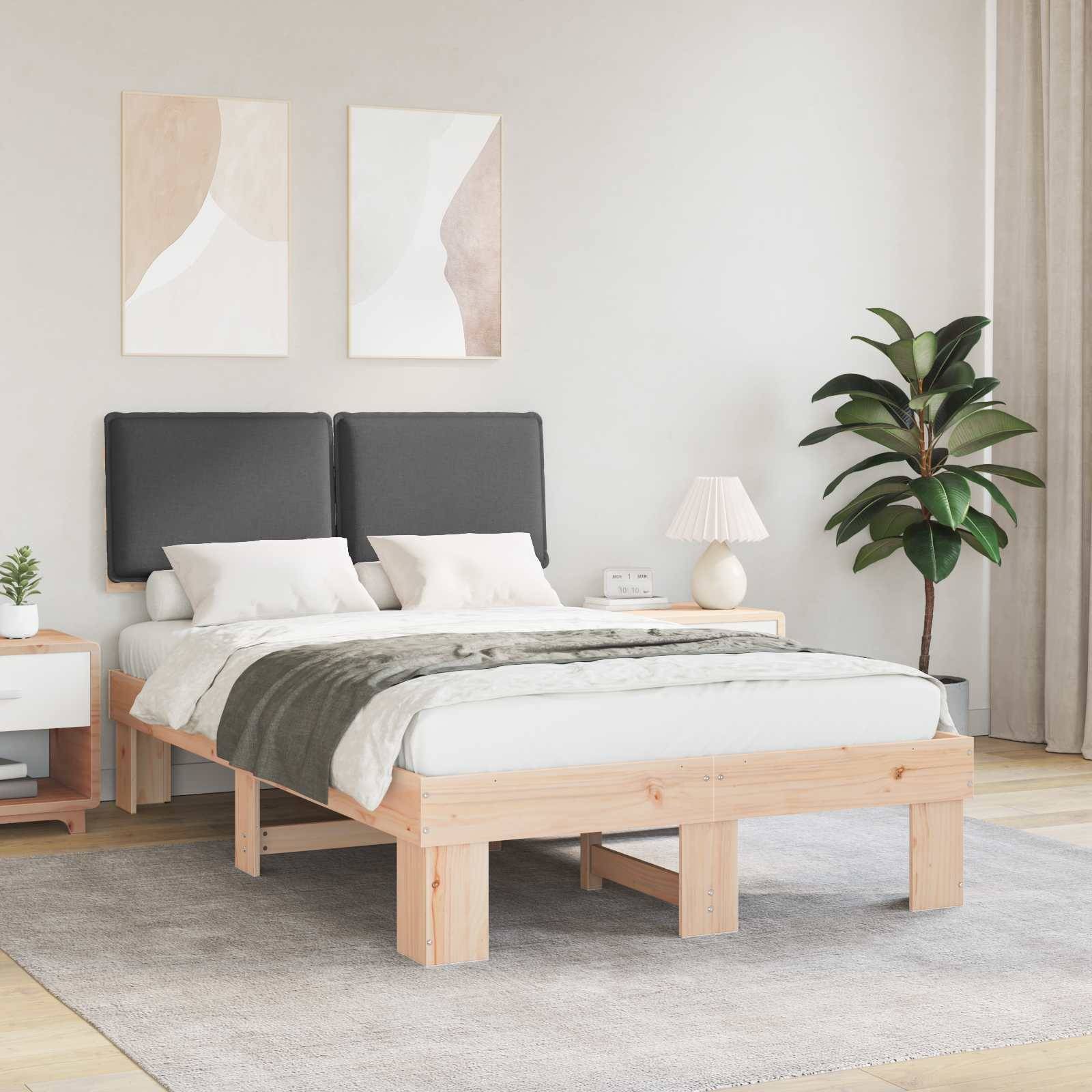 Ein modernes Schlafzimmer mit einem Holzbett, grauer Bettwäsche, grüner Decke, zwei schwarzen Kopfteilen, zwei Gemälden an der Wand und einer Zimmerpflanze.