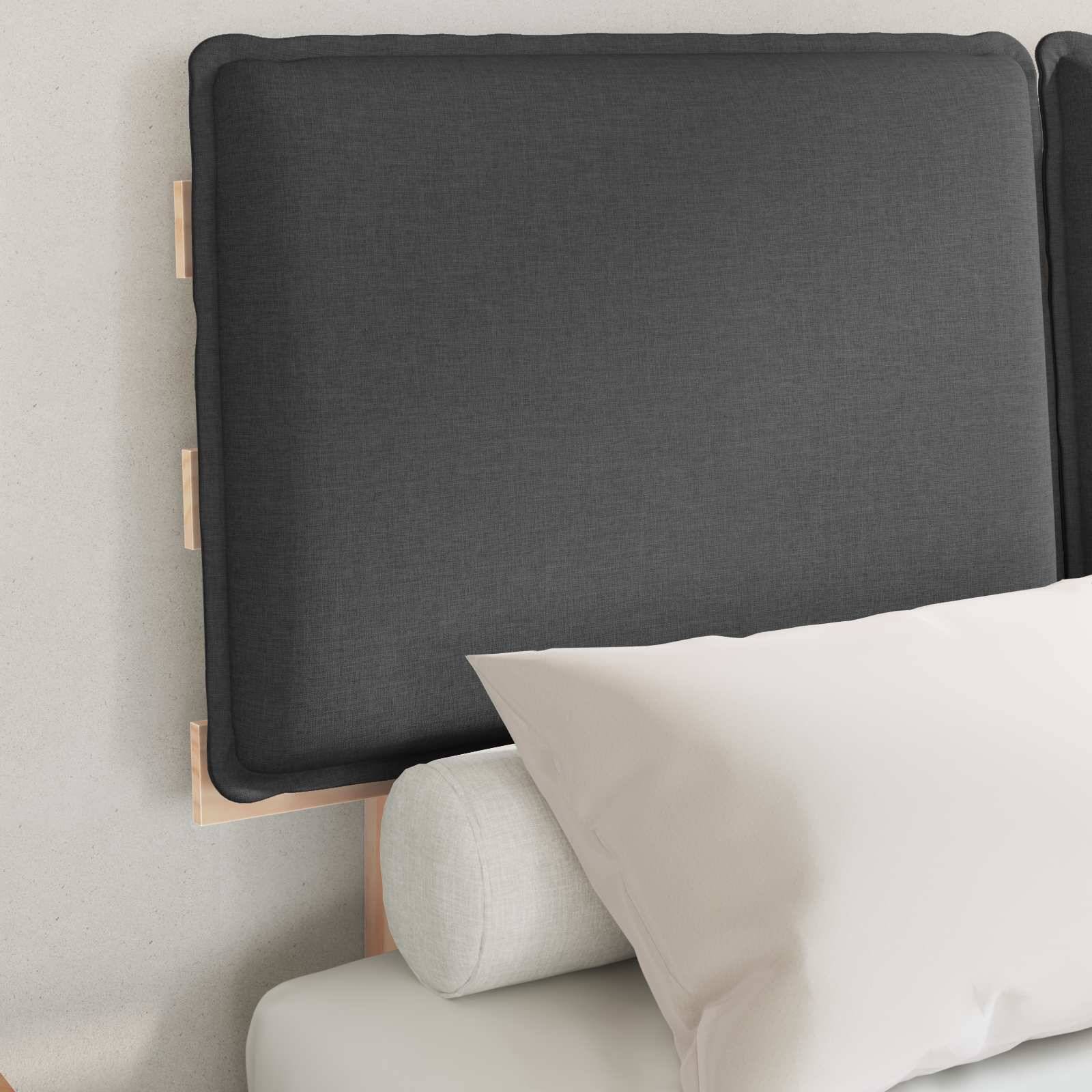 Eine einfache Betteinrichtung mit einem weichen, gepolsterten Kopfteil in neutralem Ton, versehen mit einem zylindrischen Bolster und einem weißen Kissen auf dem Bett.
