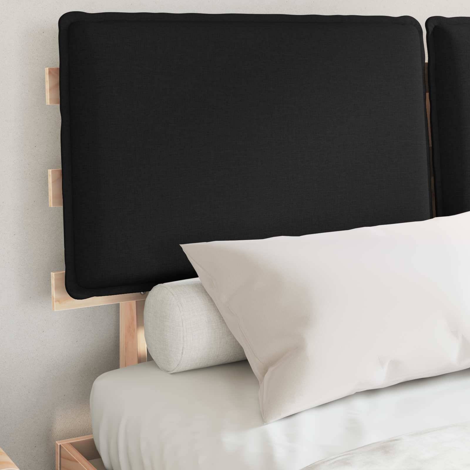 Ein ordentlich gemachtes Bett mit einem schwarzen Kopfteil, einem grauen Nackenrollo und einem weißen Kissen, das eine minimalistische Schlafzimmereinrichtung zeigt.