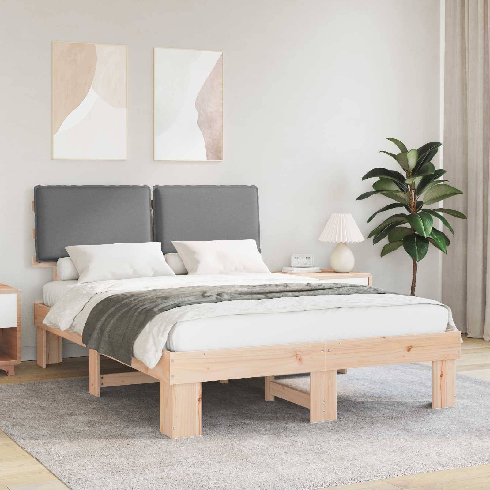 Ein modernes Schlafzimmer mit einem Holzbett, grauem Kopfteil und Bettwäsche, zwei abstrakten Gemälden, einer Nachttischlampe und einer Zimmerpflanze.