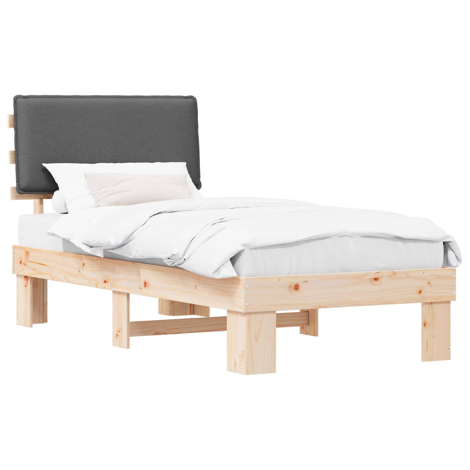 Ein Holzbettgestell mit heller Beschichtung verfügt über einen dunkel gepolsterten Kopfteil. Das Bett ist ordentlich bezogen mit weißen Laken und einem Kissen.