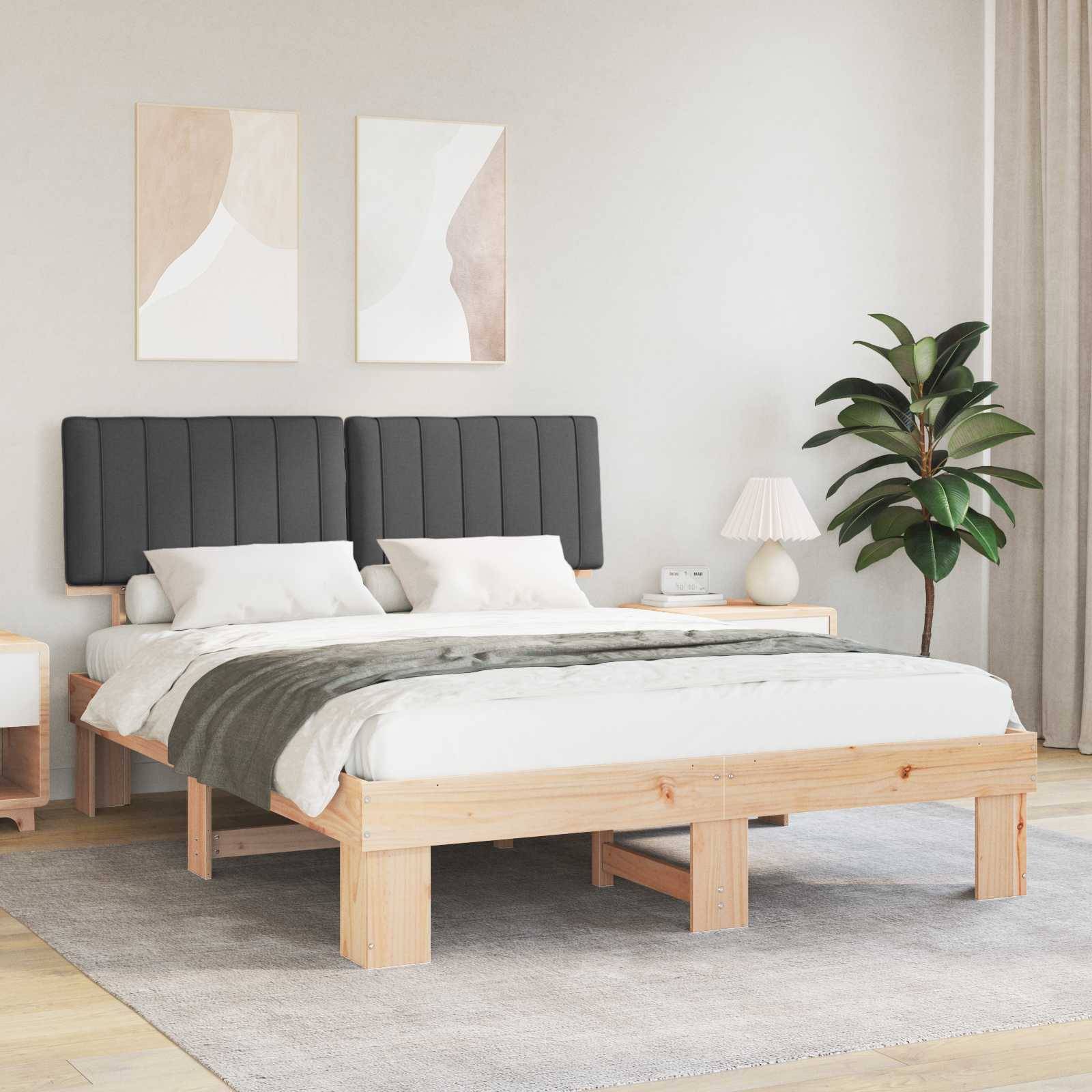 Ein modernes Schlafzimmer zeigt ein Holzbett mit grauem Kopfteil, weißer Bettwäsche, zwei Nachttischen mit Lampen, abstrakter Wandkunst und einer Topfpflanze.