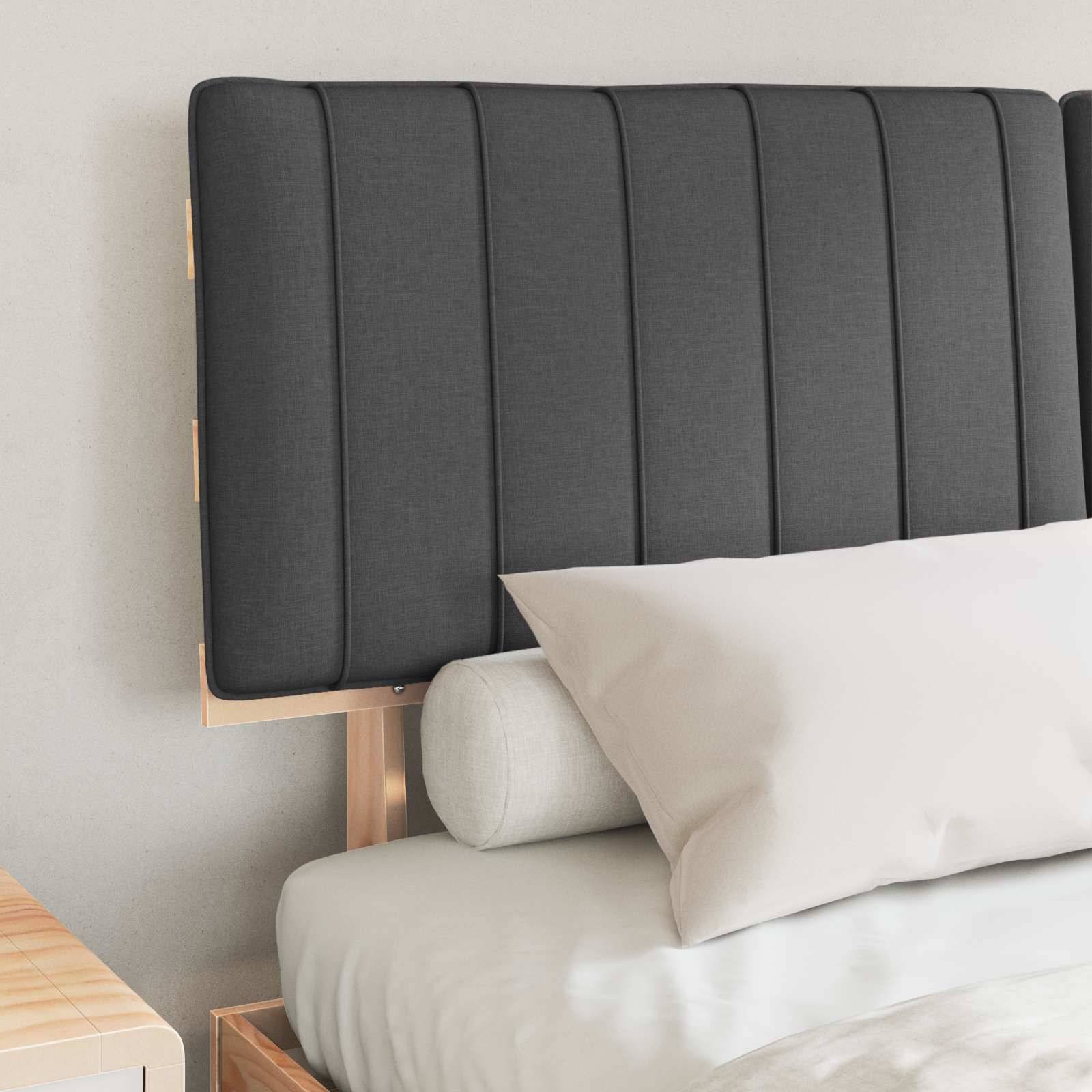 Ein Bett mit einem gepolsterten, dunkelgrauen Kopfteil, einem weißen Kissen und einem hellgrauen zylindrischen Nackenrolle.