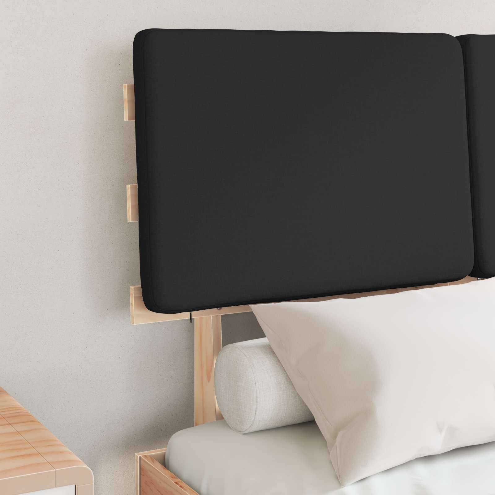 Ein modernes Bett mit einem schwarzen gepolsterten Kopfteil und weißen Kissen, die vor einer hellgrauen Wand platziert sind.