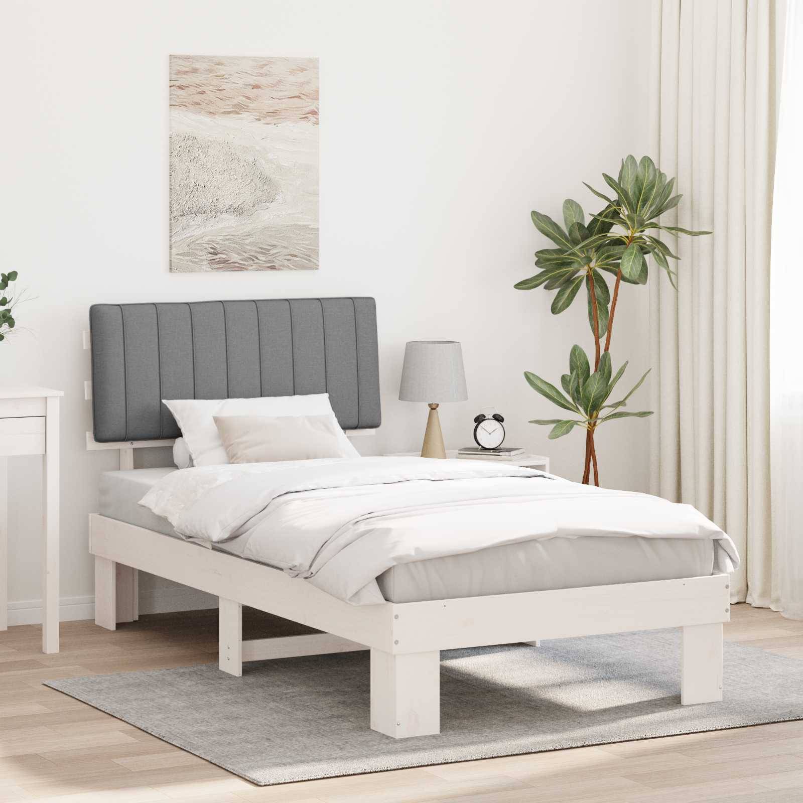 Ein minimalistisches Schlafzimmer mit einem weißen Bett, grauem Kopfteil, weißer Bettwäsche, einem Nachttisch mit einer Lampe, einer Topfpflanze und Wandkunst.