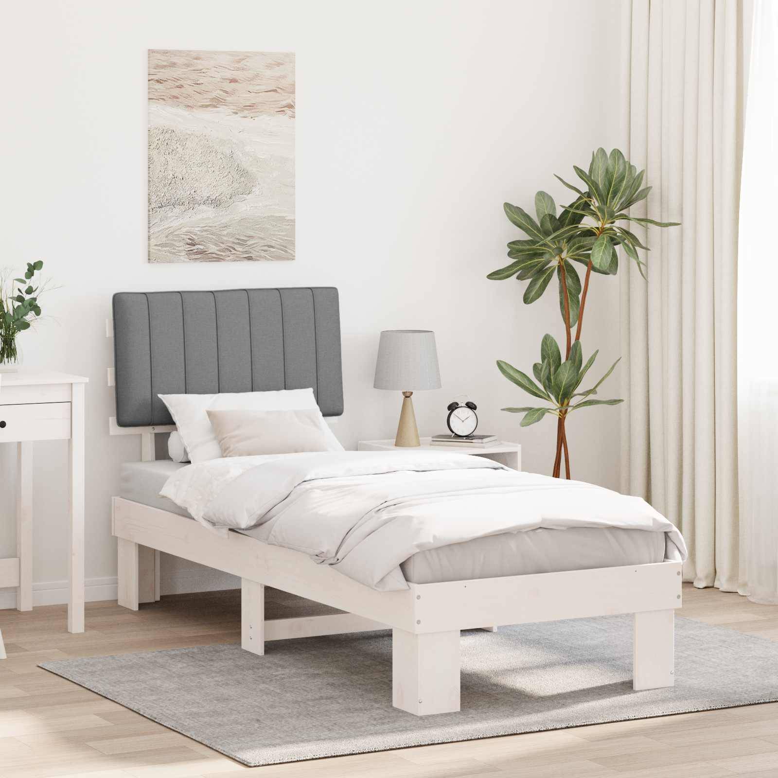 Ein minimalistisches Schlafzimmer mit einem weißen Bett, grauem gepolstertem Kopfteil, Nachttisch, Zimmerpflanze und Wandkunst. Helles Licht flutet durch die Vorhänge.