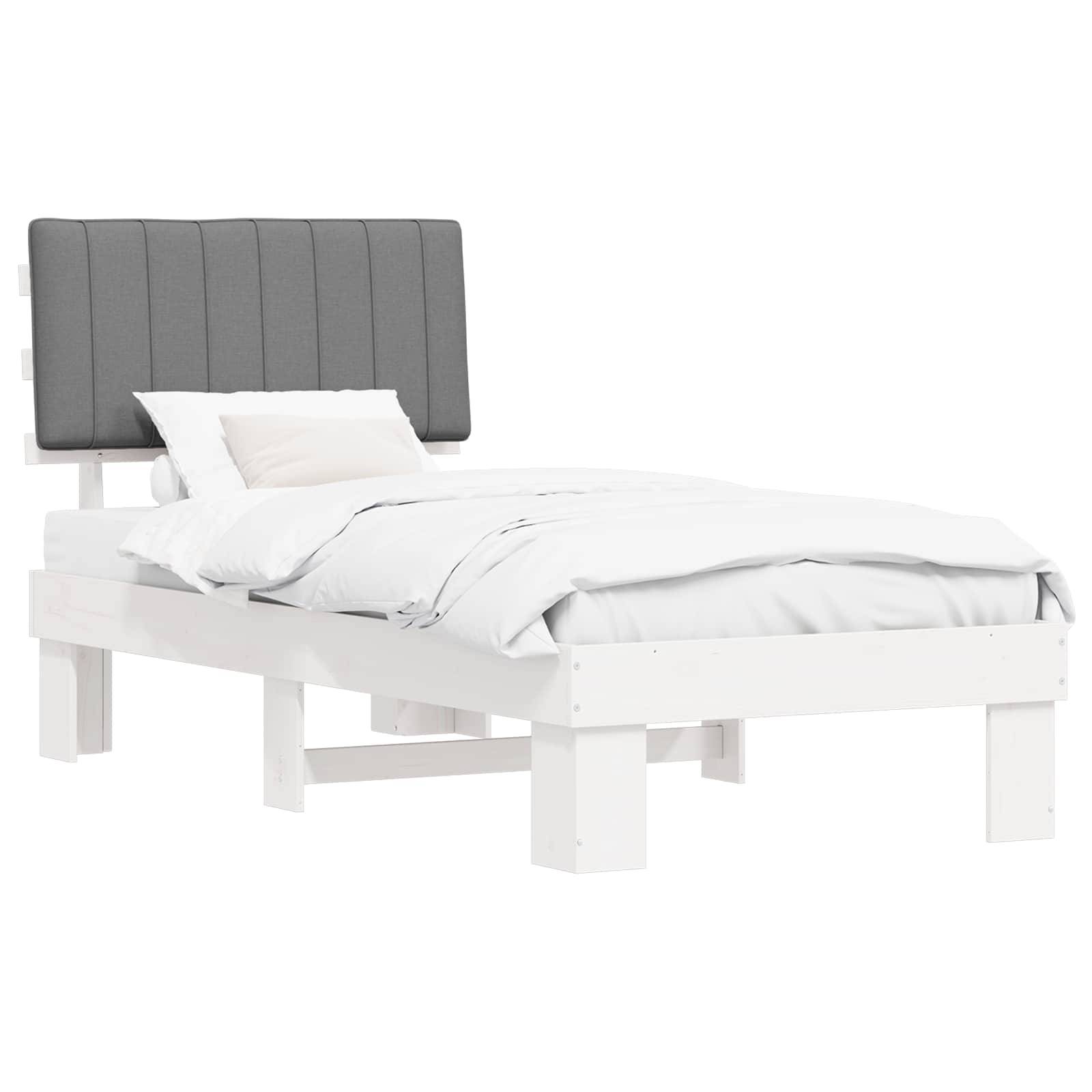 Ein weißes Einzelbett mit einem gepolsterten grauen Kopfteil, bezogen mit weißen Laken und einem Kissen, vor einem einfarbigen Hintergrund.
