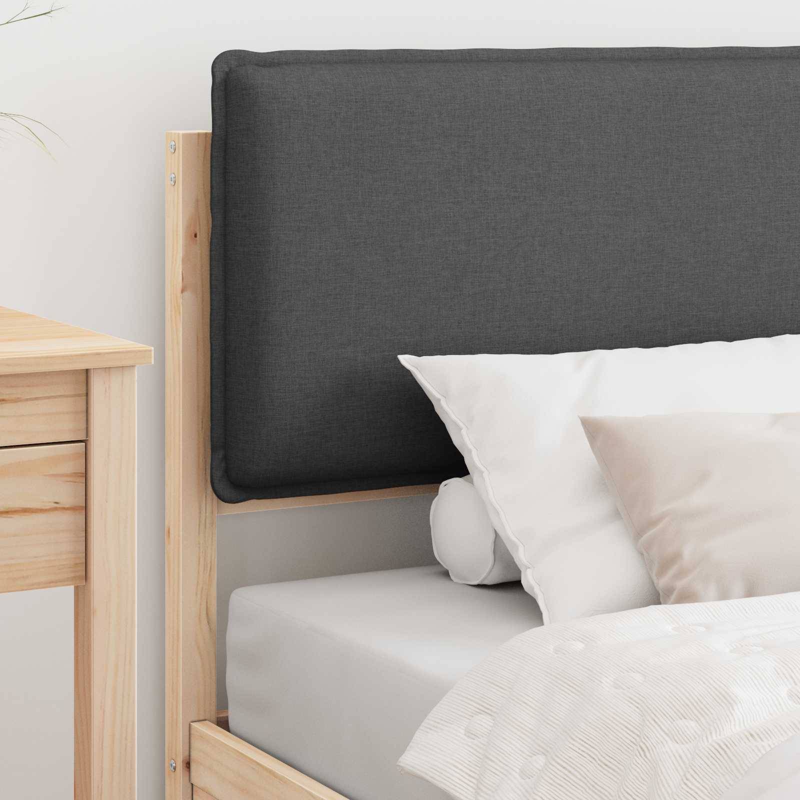 Ein sorgfältig gemachtes Bett mit einem grauen gepolsterten Kopfteil, weißer Bettwäsche und zwei Kissen, eines weiß und eines grau. Ein hellhölzerner Nachttisch ist teilweise zu sehen.