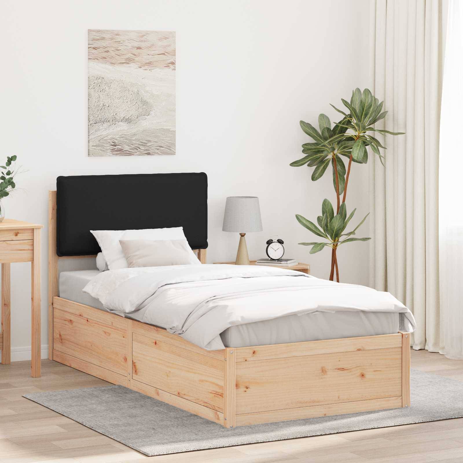 Ein aufgeräumtes Schlafzimmer mit einem Holzbett mit grauer Bettwäsche, einem Nachttisch mit einer Lampe und einer Uhr sowie einer Zimmerpflanze mit Blättern in der Ecke.