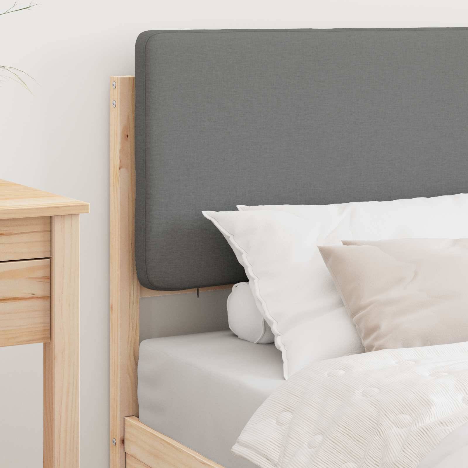Ein ordentlich gemachtes Bett mit einem grauen Kopfteil, weißer Bettwäsche und beigen Zierkissen, neben einem Nachttisch aus hellem Holz.
