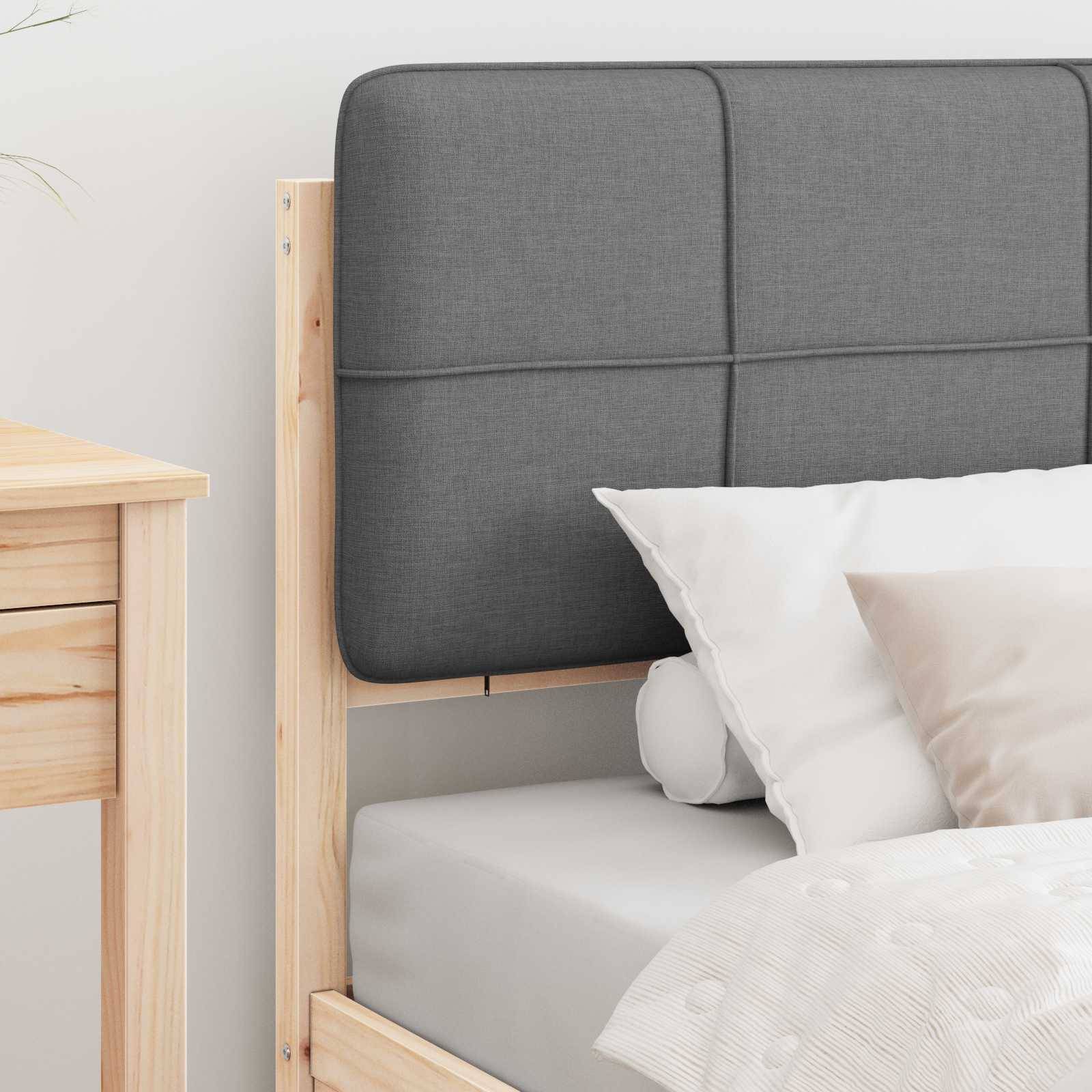 Ein ordentlich gemachtes Bett mit einem Holzrahmen, einem grauen gepolsterten Kopfteil und weißen Kissen, neben einem Holznachttisch.