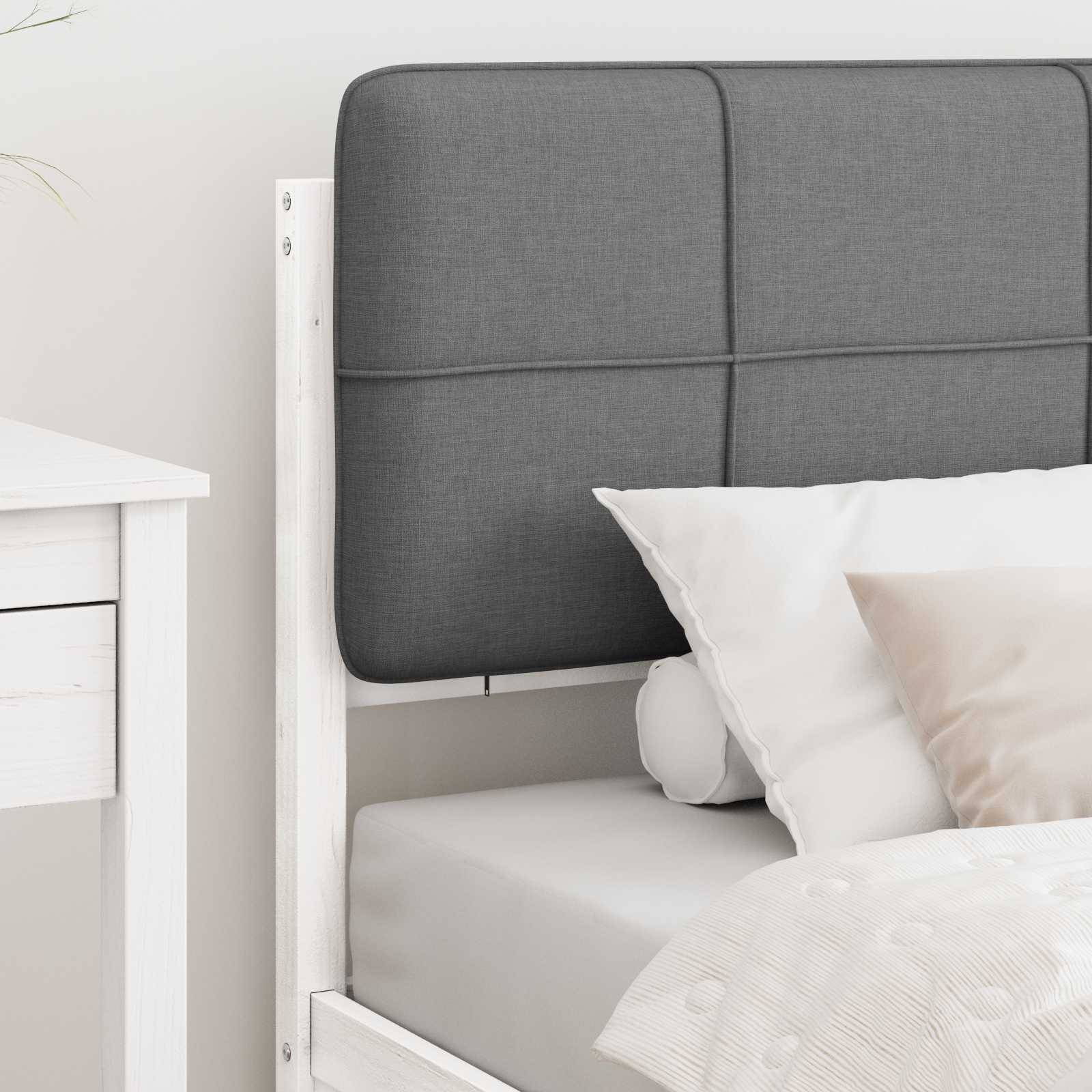 Ein ordentlich gemachtes Bett mit einem hellgrauen Kopfteil, weißen Kissen und einer beigen Decke, neben einem weißen Nachttisch mit einer Schublade.