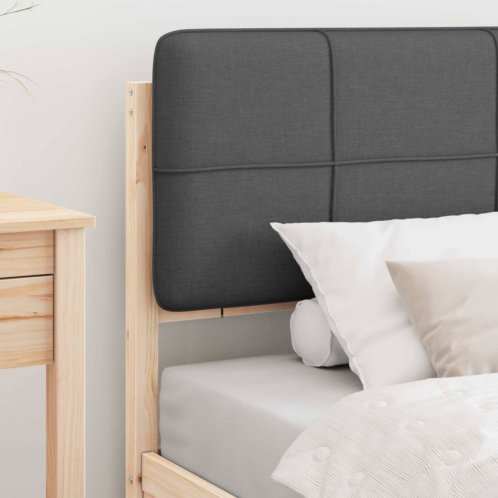 Ein ordentlich gemachtes Bett mit einem grauen Kopfteil, weißen Kissen und einer strukturierten weißen Bettdecke in einem hellen Raum neben einem Holznachttisch.