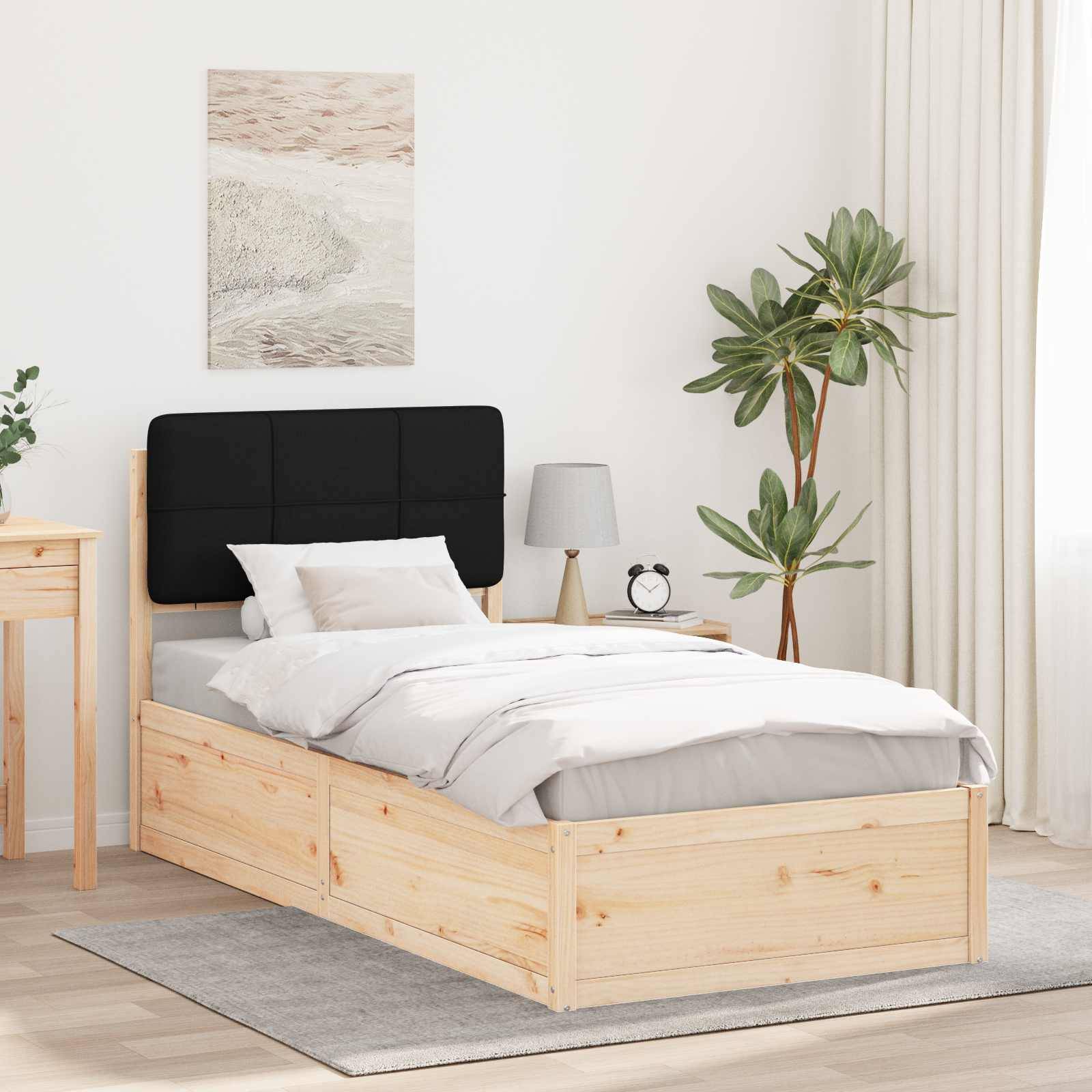 Ein sauber gemachtes Einzelbett mit einem schwarzen Kopfteil in einem minimalistischen Schlafzimmer, ausgestattet mit einer Topfpflanze, einem Nachttisch mit einer Lampe und Wandkunst.