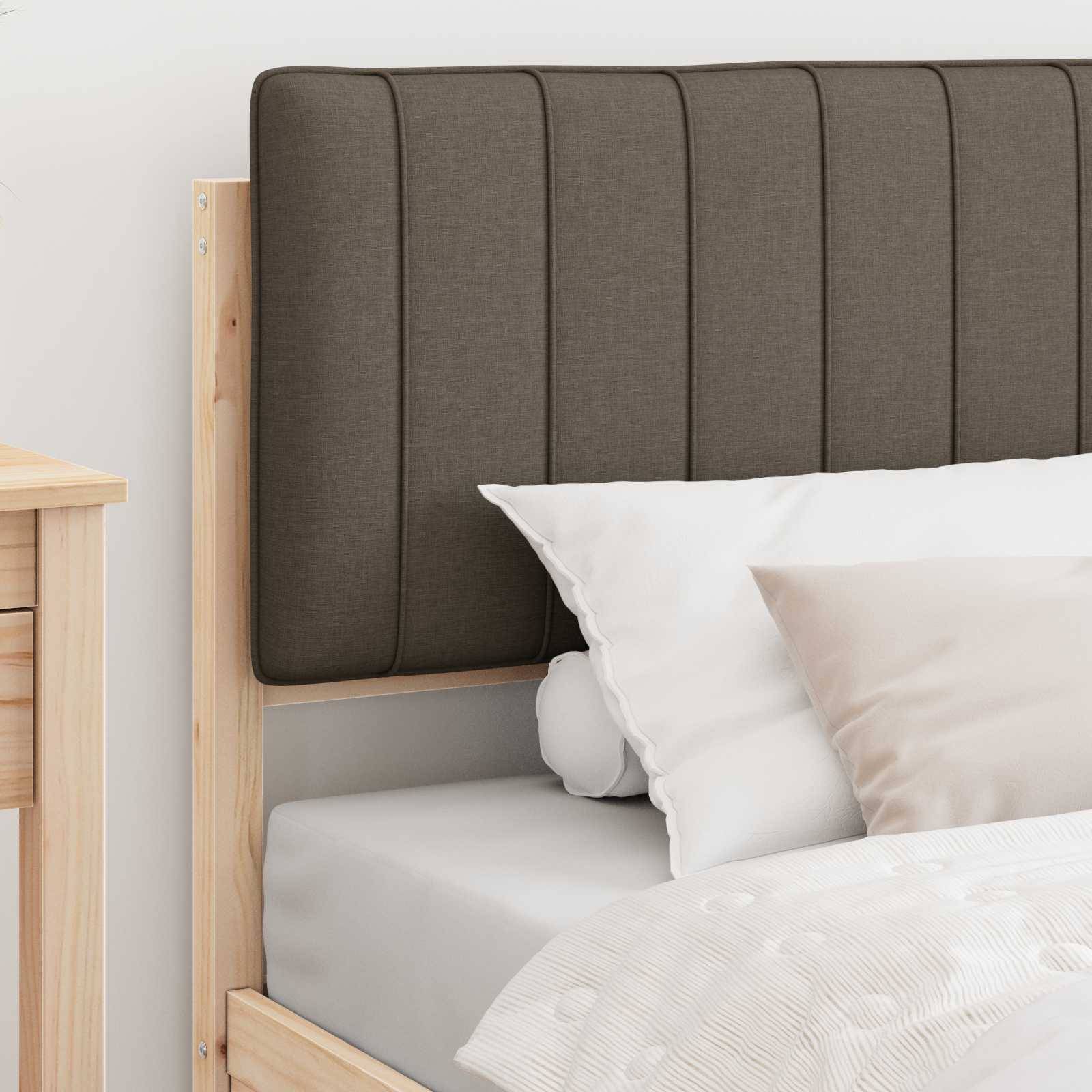 Ein Bett mit einem Holzrahmen, einem dunkel gepolsterten Kopfteil und weißer Bettwäsche. Ein hellhölzerner Nachttisch ist teilweise neben dem Bett zu sehen.