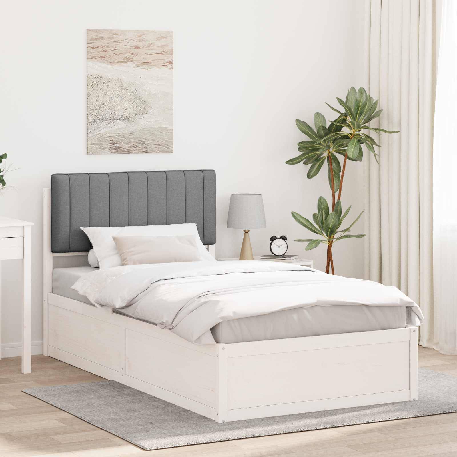 Ein ordentlich gemachtes Bett mit einem grauen Kopfteil wird von einem Nachttisch mit einer Lampe und einer Zimmerpflanze flankiert, was eine ruhige Schlafzimmeratmosphäre schafft.