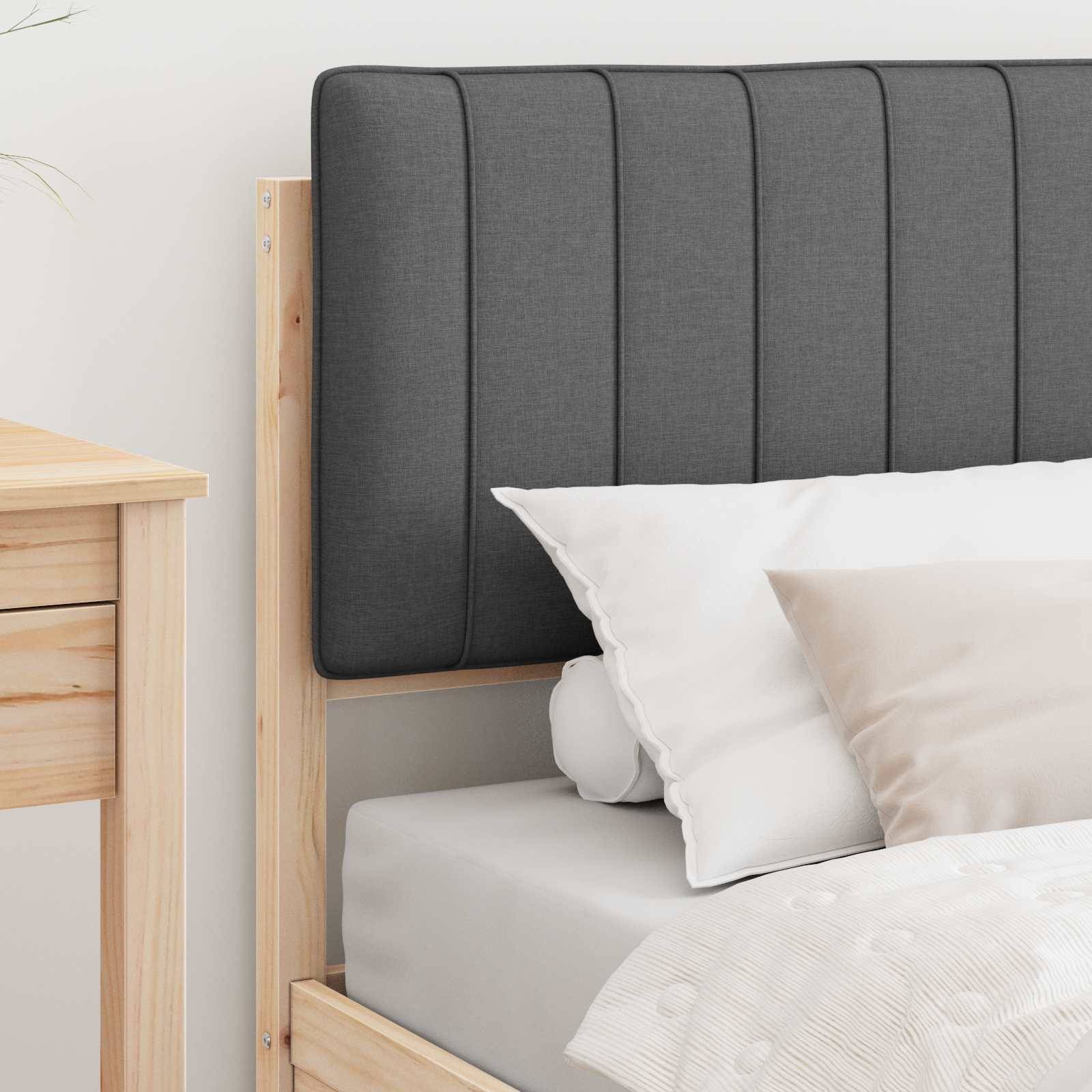 Eine gemütliche Schlafzimmer-Szene mit einem Holzbettgestell, einem gepolsterten grauen Kopfteil, weißer Bettwäsche und einem hellbraunen Nachttisch in der Ecke.