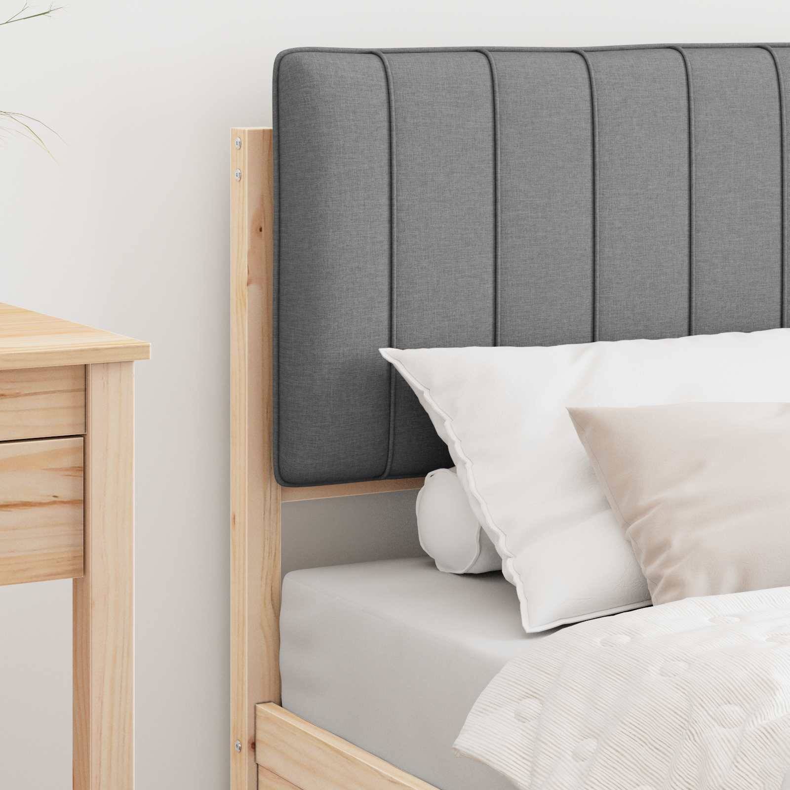 Ein ordentlich gemachtes Bett mit einem grauen gepolsterten Kopfteil, weißen Kissen und einer beigen Bettdecke steht neben einem Holznachttisch.