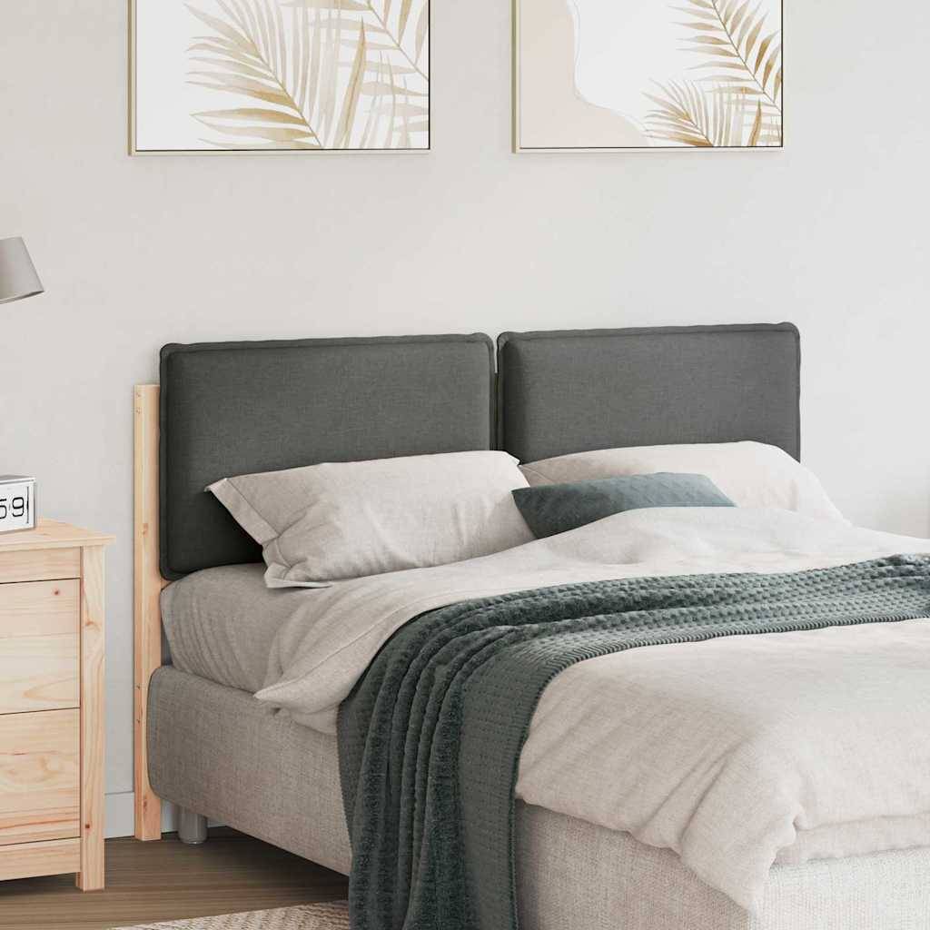 Ein sauber gemachtes Bett mit einem dunkelgrauen Kopfteil, heller Bettwäsche, einer grünen Decke und zwei gerahmten Blätterdrucken darüber. Ein Holznachttisch trägt einen digitalen Wecker.