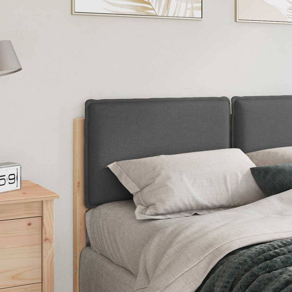 Ein sauber gemachtes Bett mit grauem Kopfteil und beiger Bettwäsche, neben einem Holznachttisch mit einer Lampe und einem kleinen Dekoschild.