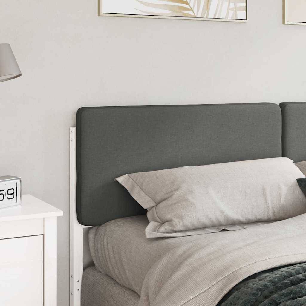 Ein sauber gemachtes Bett mit grauem Kopfteil, weißer Bettwäsche und einem Nachttisch mit Lampe und Uhr in einer sanft beleuchteten Schlafzimmerumgebung.