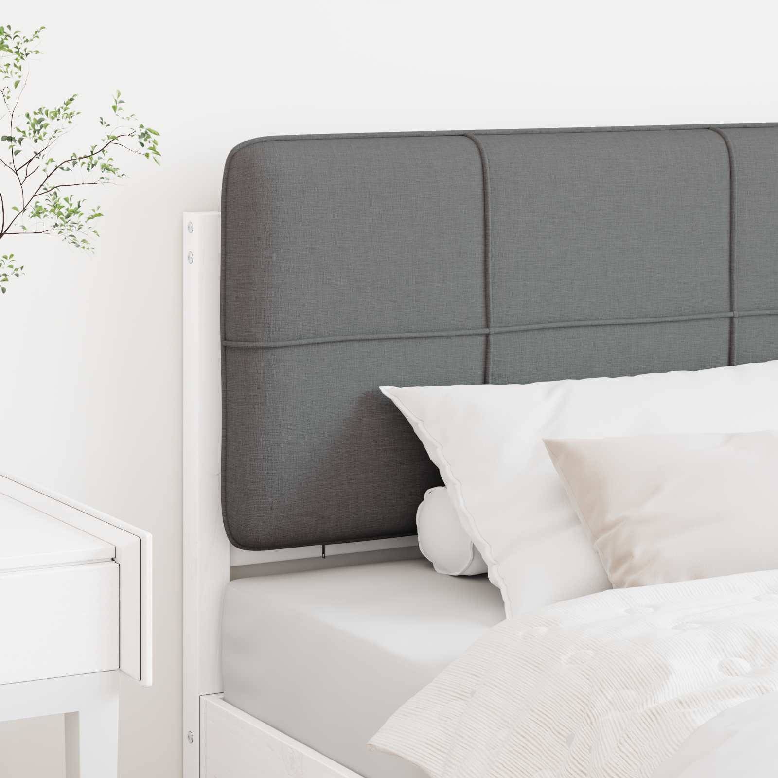 Ein modernes Schlafzimmer mit weißem Bett, grauem Kopfteil und weißem Kissen. Eine kleine Pflanze steht auf einem weißen Nachttisch links.