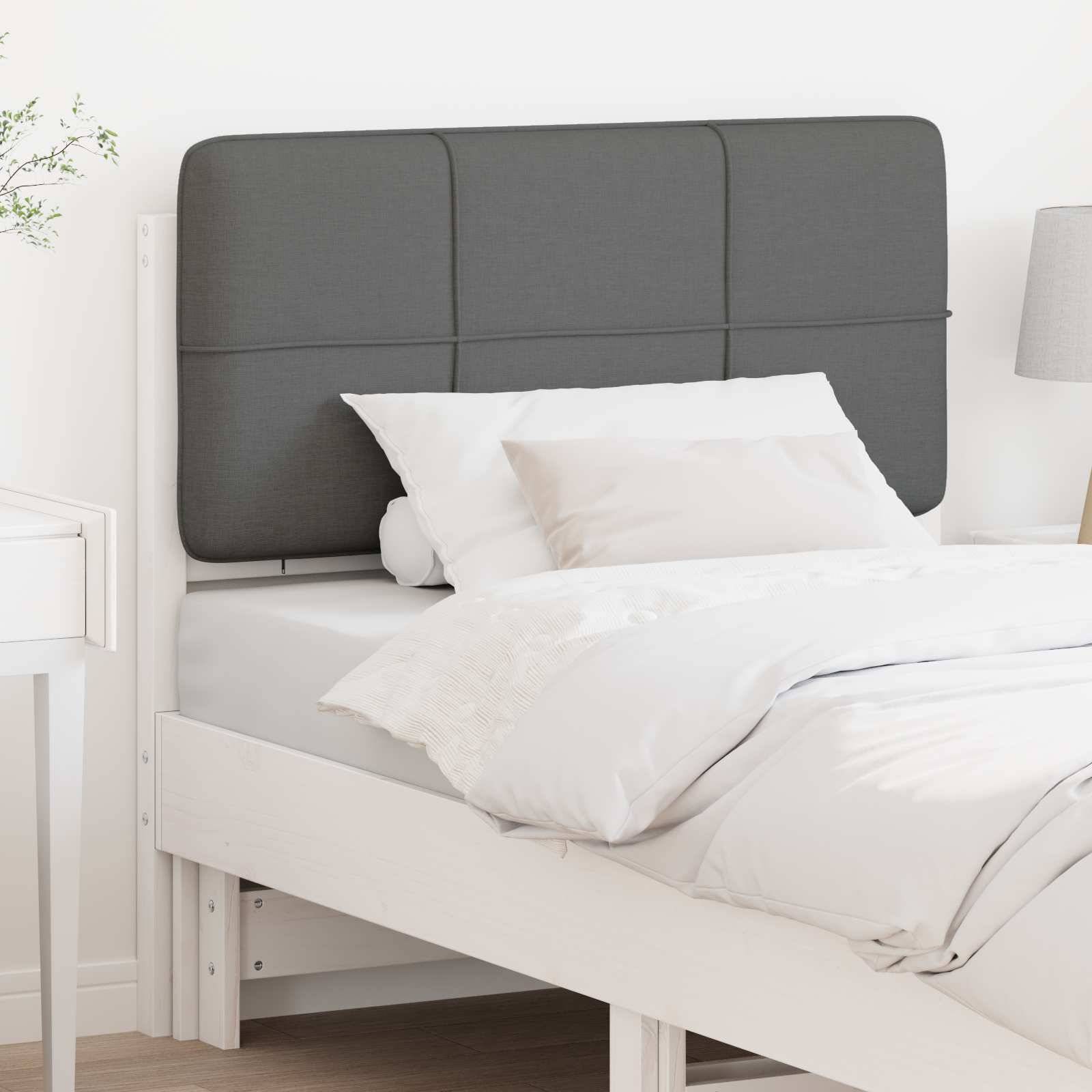 Ein weißes Bett mit einem dunklen Kopfteil, ausgestattet mit weißen Kissen und einer ordentlich arrangierten Bettdecke, positioniert neben einem weißen Nachttisch.