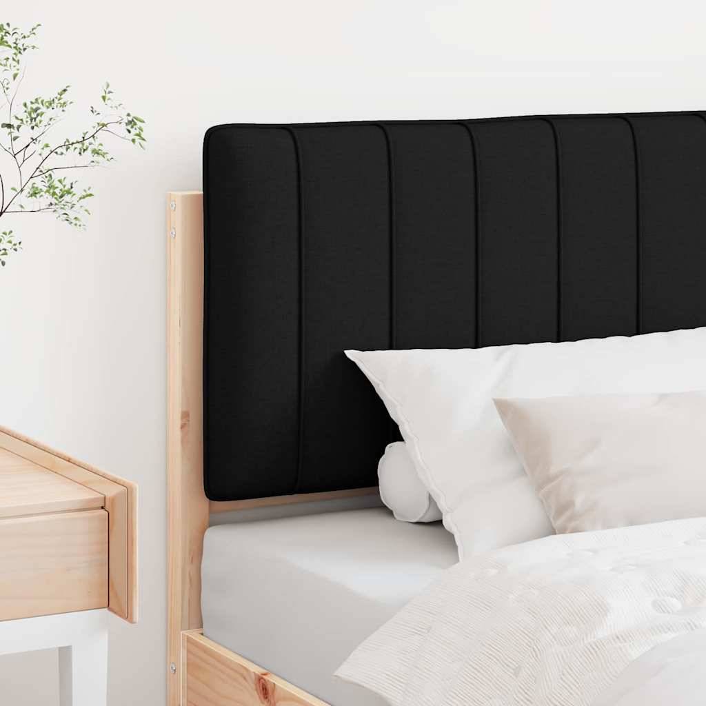 Ein gemütliches Bett mit einem schwarzen Kopfteil und weißer Bettwäsche, positioniert neben einem hellholzfarbenen Nachttisch und einer Pflanze im Hintergrund.