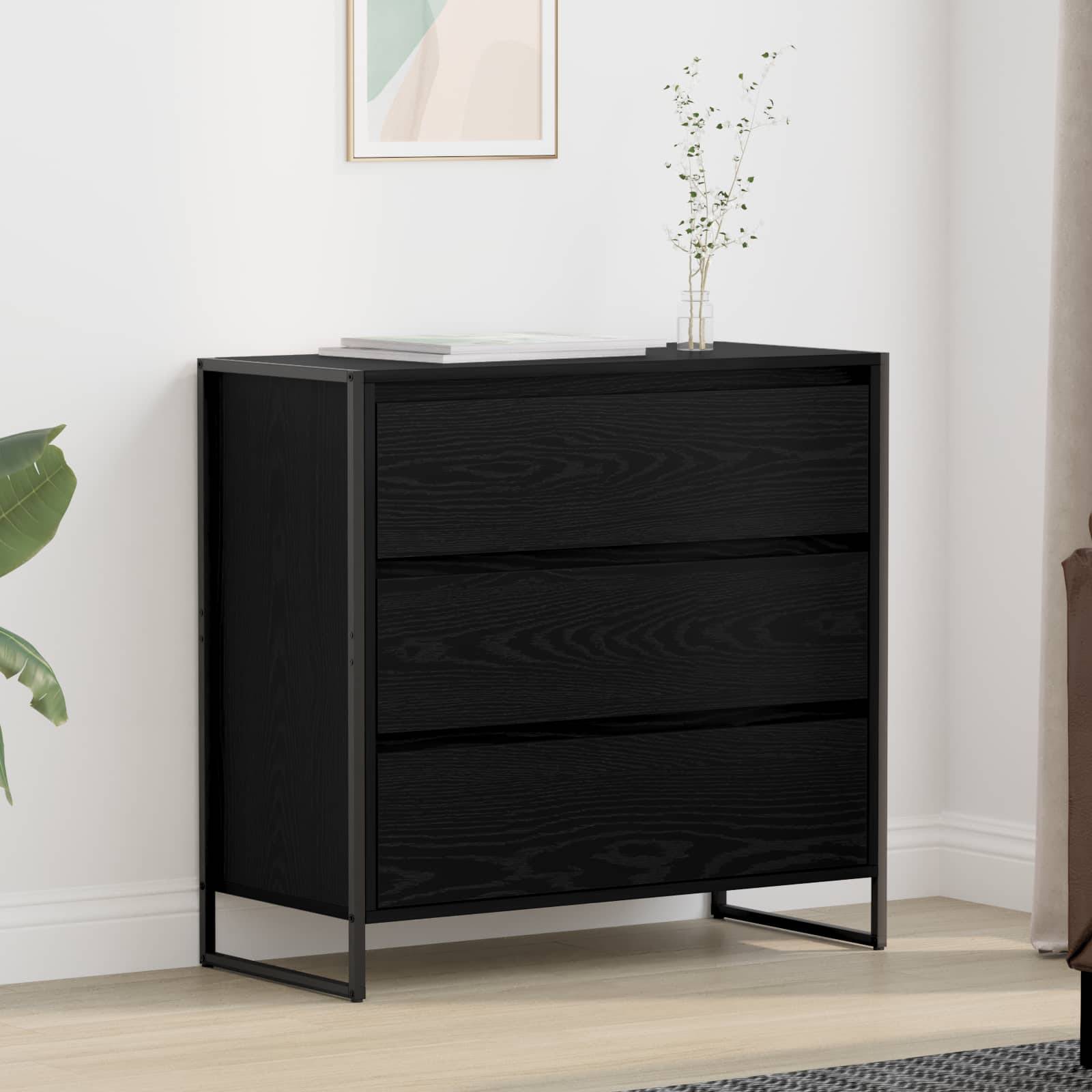 Ein schwarzer Dreischubladen-Schrank steht an einer weißen Wand, verziert mit einem minimalistischen gerahmten Kunstwerk und einer kleinen Blumenvase auf der Oberfläche.
