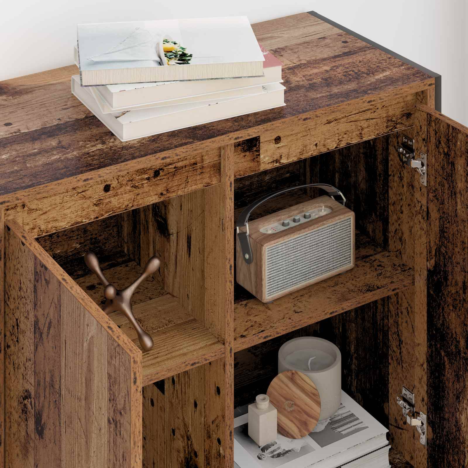 Holzschrank mit offenen Türen, der ein Radio, eine Kerze und Bücher im Inneren zeigt. Bücher sind oben gestapelt. Der Schrank hat eine rustikale Oberfläche.