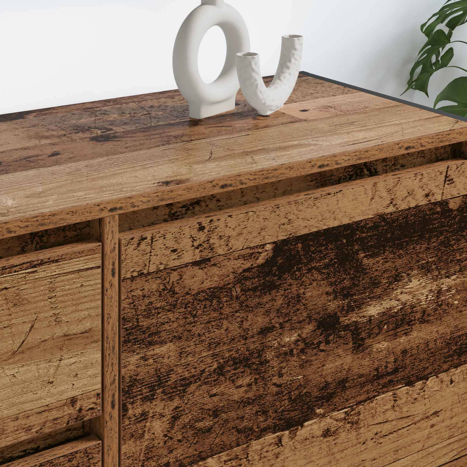 Ein Holzsideboard mit einer strukturierten Oberfläche trägt eine weiße, abstrakte Skulptur. Im Hintergrund ist eine grüne Pflanze teilweise zu sehen.